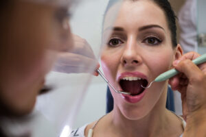 dentist-examining-female-patient-with-tools-scaled to prevent gum disease with periodontal treatment