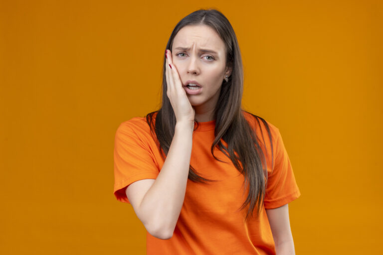 A young woman with teeth pain holding mouth with hands, facing gum disease