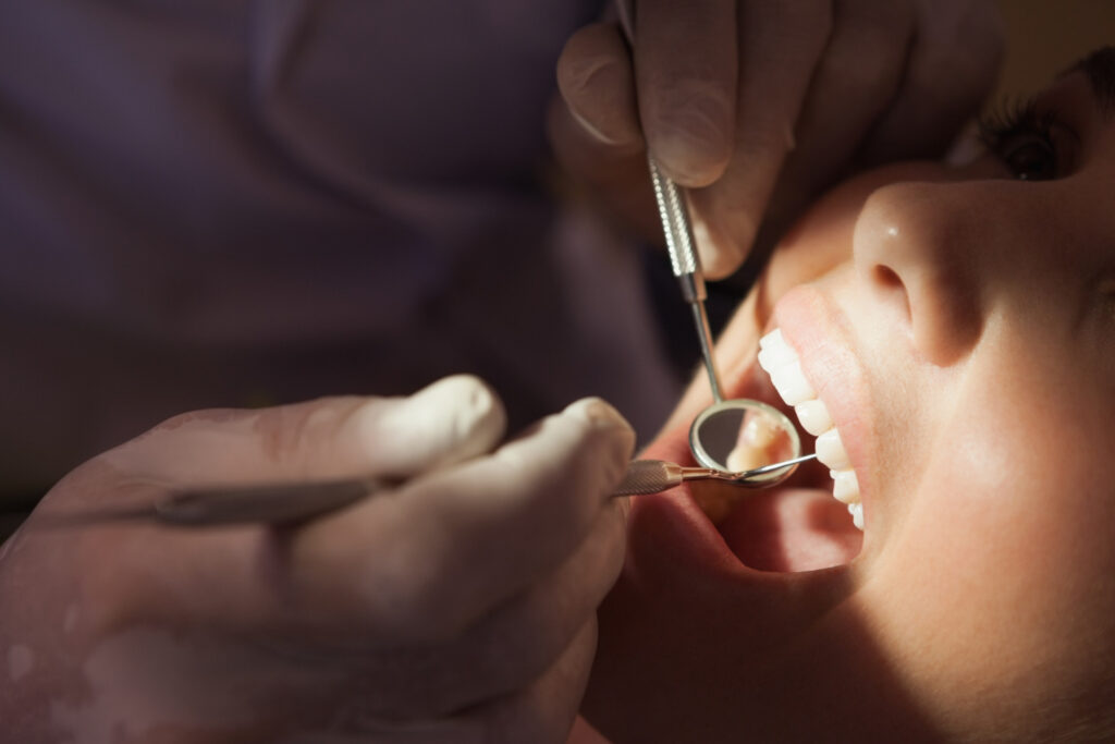 Dentist examining a patient's teeth with a dental mirror during a dental evaluation before a tooth extraction in Reading, PA.