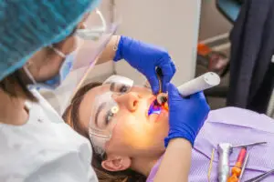 Dentist performing laser periodontal therapy on a patient during gum disease treatment with protective dental equipment.