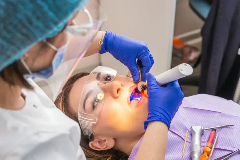 Dentist performing laser periodontal therapy on a patient during gum disease treatment with protective dental equipment.
