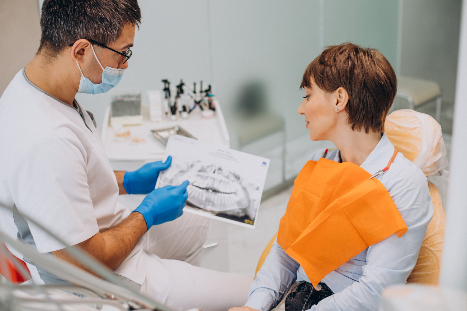 Dentist explaining dental X-ray results to a patient during a periodontal consultation.
