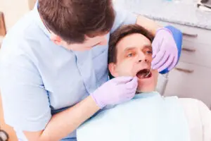Dentist examining a patient’s gums during a periodontal dental examination for gum recession treatment.