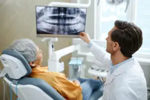 Dentist reviewing a dental X-ray with a patient during a dental implant bone regeneration consultation in Reading, PA.