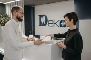 Dentist discussing treatment options with a patient at a dental clinic reception desk.