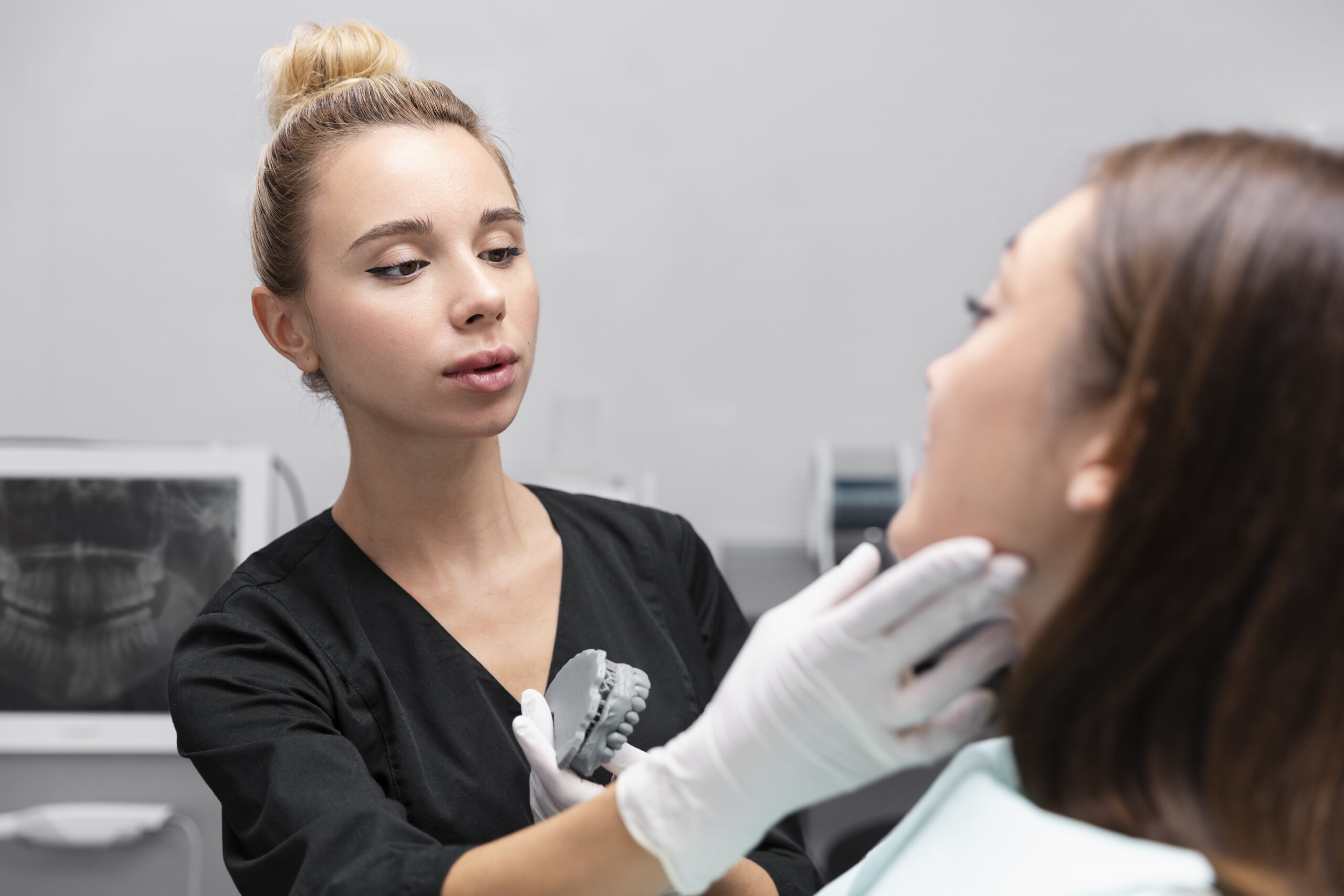 Periodontist examining a patient for jawbone loss treatment with an X-ray visible during dental evaluation and planning.